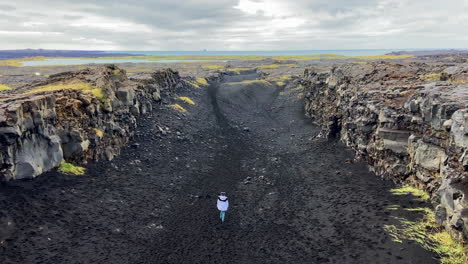 Woman-walking-on-epic-path-between-American-and-Eurasian-tectonic-plates,-Iceland