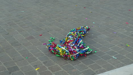 Colorful-candy-wrappers-strewn-on-cobblestone-after-a-parade
