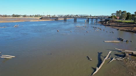 Over-many-dead-trees-lying-in-the-shallow-water-of-Lake-Mulwala-with-the-road-bridge-beyond
