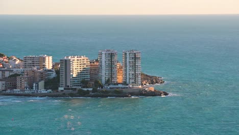 Footage-of-a-group-of-large-tourist-apartment-buildings-among-the-Mediterranean-Sea-and-its-deep-blue-water-in-Spain
