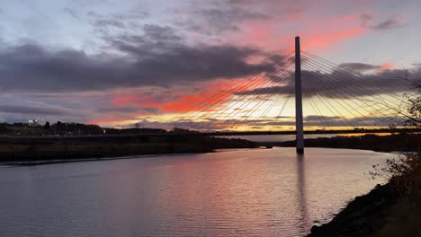 The-Northern-Spire-Bridge-over-the-River-Wear-in-Sunderland,-England,-during-a-dramatic-orange-autumn-sunset