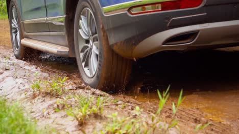 A-close-up-of-a-car-passing-through-a-dirt-road-in-Argentina,-navigating-through-a-mud-puddle