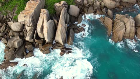 Bird-eye-drone-shot-of-hidden-beach-near-north-east-point-beach,-huge-rock-boulders,-white-sandy-beach-and-turquoise-water,-Mahe-seychelles-60fps