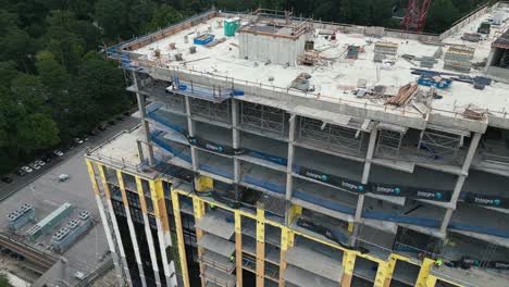 Aerial-top-down-of-skyscraper-Building-at-building-phase-with-construction-site-on-rooftop-in-Atlanta-City---Parking-cars-on-the-ground---orbiting-flight