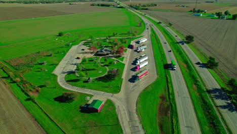 Luftaufnahme-Der-Raststätte-Illinois-Prairie-Richtung-Norden,-Geparkte-Lastwagen-Machen-Eine-Pause,-Während-Der-Autoverkehr-Auf-Der-Straße-In-Ihrer-Nähe-Einwandfrei-Verläuft