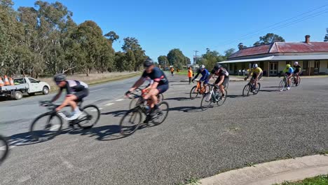Wilby,-Victoria,-Australia---21-August-2022:-A-group-of-road-race-cyclists-rounding-a-bend-in-the-township-of-Wilby,-Victoria,-Australia