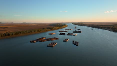 Aerial-tracking-wide-shot-of-anchored-barges-on-a-big-blue-river,-clear-sunny-day,-4K50Fps