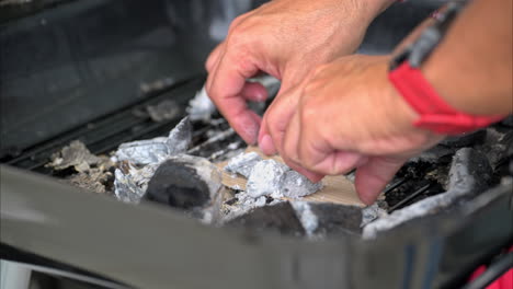 Slow-motion-of-male-hands-setting-up-burnt-charcoal-to-start-a-fire-for-a-grill-using-cardboard