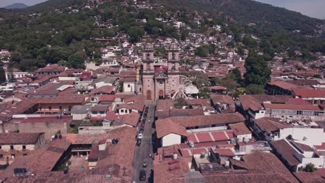 A-drone-flies-over-the-houses-in-the-center-of-Valle-de-Bravo,-approaching-the-two-towers-of-the-Parish-of-San-Francisco-de-Asís