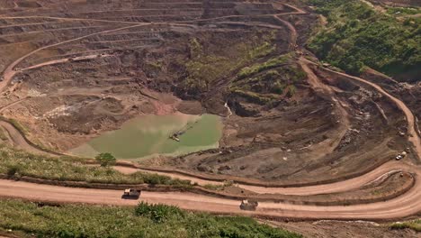 An-aerial-drone-shot-of-dirt-roads-with-trucks-driving-around-Siana-Gold-and-Silver-mine-in-Mainit,-Philippines