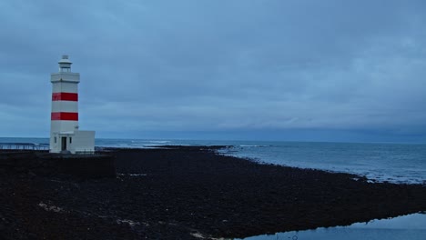 Stunning-view-of-an-old-lighthouse-on-black-sand-beach-in-Iceland