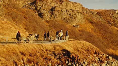 Touristen,-Die-An-Einem-Sonnigen-Tag-über-Den-Pfad-Auf-Dem-Berg-In-Der-Nähe-Des-Gullfoss-Wasserfalls-In-Island-Laufen