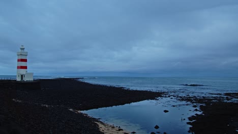 Pan-Desde-El-Mar-En-Calma-Hasta-Un-Antiguo-Y-Pintoresco-Faro-En-Gardur,-Islandia