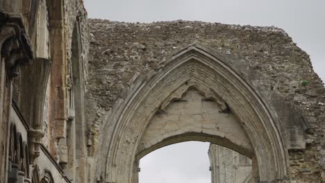 Glastonbury-Abbey-ruins,-detail-of-a-wall-with-gothic-arch-4k-slow-motion