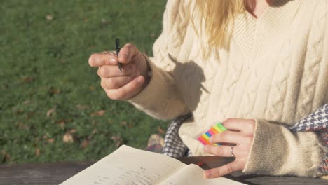 A-woman-bookmarks-page-while-studying-outdoors