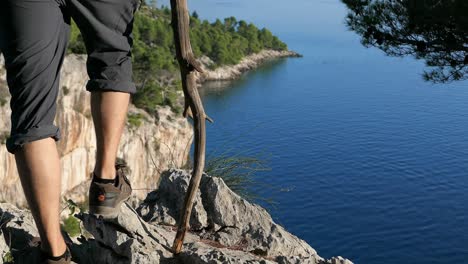 Traveler-conquering-a-mountain,-hiker-on-the-edge-of-mountain-top-with-sea-view