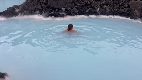 Bonita-Mujer-Nadando-Felizmente-En-Un-Spa-Termal-De-Agua-Azul-Volcánica.