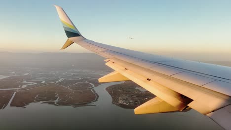 Alaska-plane-approaching-San-Francisco-airport,-flying-low-over-wetlands-with-second-plane-above-wing