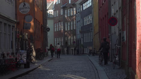 Cobblestone-alley-with-pedestrians-and-bicycles-in-Copenhagen,-Denmark