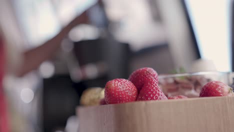 Nahaufnahme-Von-Erdbeeren,-Während-Eine-Frau-Im-Hintergrund-Kaffee-Zubereitet