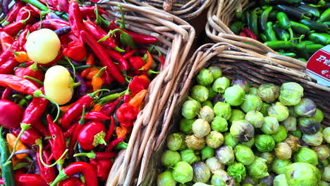 Spicy-chilli-peppers,-jalapeño-peppers-and-green-tomatillos,-fresh-vegetables-from-the-local-farm-for-sale-at-an-organic-farmers-market,-healthy-bio-greens,-4K-shot