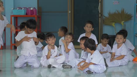 Junge-Thailändische-Schüler-Stehen-Vereint-Da,-Winken-Fröhlich-In-Die-Kamera-Und-Verkörpern-In-Ihren-Weißen-Schuluniformen-Die-Lebendigkeit-Der-Bildung