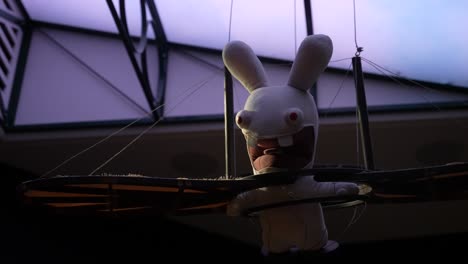Raving-Rabbid-mascot-from-the-Futuroscope-theme-park-hanging-from-the-ceiling,-Looking-up-shot