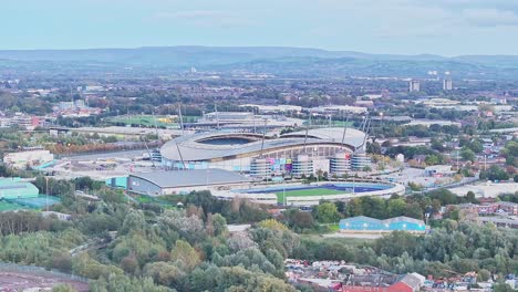 Drone-wide-shot-showing-soccer-area-of-Manchester-City-with-training-ground-and-Etihad-Stadium-at-dusk