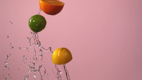 Citrus-Fruits-And-Water-Fly-Through-The-Air-In-Front-Of-A-Pink-Background