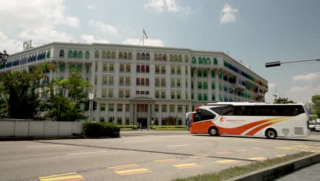 Das-Farbenfrohe-Gebäude-Des-Ministeriums-Für-Kommunikation-Und-Information-Auf-Der-Hill-Street-In-Singapur,-An-Dem-An-Einem-Sonnigen-Tag-Der-Verkehr-Vorbeifährt