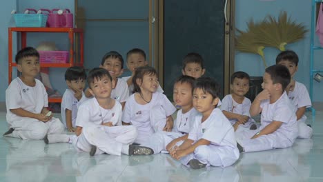 Thai-school-kids,-donned-in-crisp-white-uniforms,-joyfully-wave-to-the-camera,-radiating-the-spirit-of-youth-and-education