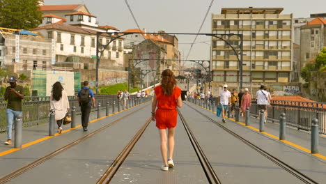 Following-shot-of-a-female-walking-on-the-top-level-of-Dom-Luís-I-Bridge,-where-the-subway-passes-in-Porto,-Portugal-during-morning-time