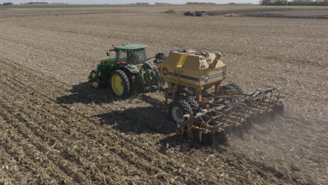 Tractor-Pulling-Strip-Till-Machine,-Preparing-Soil-on-Farm-Field-for-Planting,-Aerial
