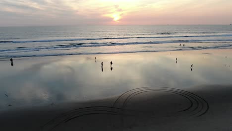 Silhouette-Von-Menschen,-Die-Bei-Sonnenuntergang-Am-Ufer-Des-Huntington-Beach-Spazieren,-Kalifornien,-Luftaufnahme