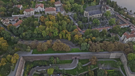 Prague-Czechia-Aerial-v118-birds-eye-view-flyover-Vysehrad-Castle-and-Brick-Gate-on-the-hill,-tilt-up-capturing-Smichov-cityscape-across-Vltava-river-at-dusk---Shot-with-Mavic-3-Cine---November-2022