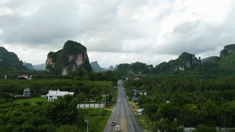 Aerial-view-of-the-scenic-highway-between-palm-tree-forest-and-limestone-cliffs-near-Ao-Nang-in-Krabi-province,-Thailand