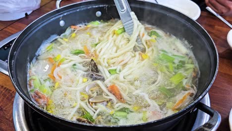 Tongs-Mix-Knife-Cut-Noodle-Soup-While-Cooking---Seafood-Clam-Kalguksu-Boiling-in-Pot