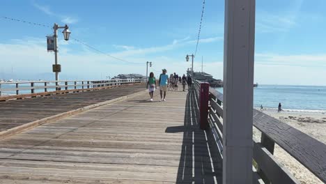 Sunny-day-and-people-enjoying-the-walk-on-wooden-Santa-Barbara-Pier-on-Californian-coast