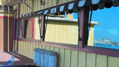 Leichte-Brise-Bewegte-Markise-Und-Spiegelung-Am-Fenster-Von-Wasser-Und-Booten-Mit-Möwen-Im-Fisherman&#39;s-Wharf-Restaurant-In-Monterey