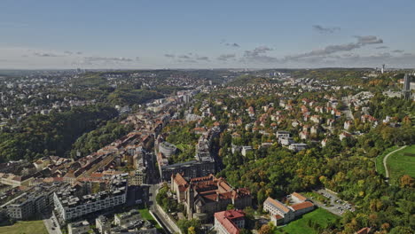 Prague-Czechia-Aerial-v46-drone-flyover-Smichov-capturing-leafy-residential-neighborhood,-Petrin-hill-featuring-Great-Strahov-Stadium-on-hilltop-and-cityscape---Shot-with-Mavic-3-Cine---November-2022