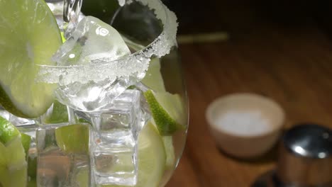 Close-up-water-filling-Fresh-cocktail-lemonade-glass-spinning-,-drink-with-soda,-lemon-slice,-ice-and-mint