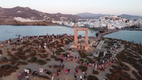 Turistas-Disfrutando-De-La-Puesta-De-Sol-En-El-Templo-De-Apolo-De-La-Isla-De-Naxos,-Grecia,-Vista-Aérea
