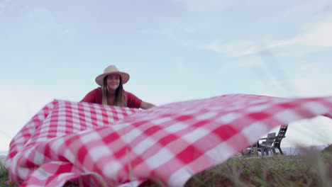 Woman-arranging-a-picnic-tablecloth-on-the-lawn