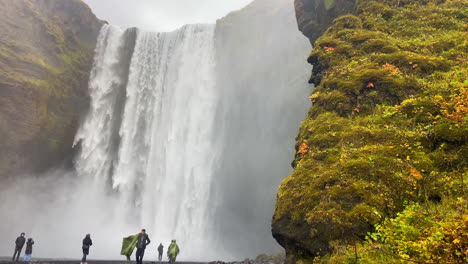 People-in-raincoats-visiting-the-incredible-Skogafoss-waterfall-in-Iceland