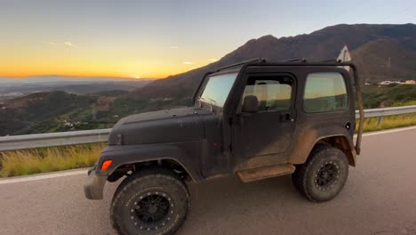 Black-Jeep-4x4-car-with-beautiful-orange-sunset-on-a-mountain,-fun-ATV-adventures-in-Marbella-Malaga-Spain,-4K-shot