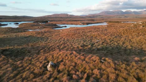 Aerial-dolly-shot-of-the-scenic-landscape-of-ireland-at-the-connemara-lakes-with-a-view-of-the-wide-landscape-in-autumnal-golden-tones-and-the-reflecting-lake-at-the-golden-hour