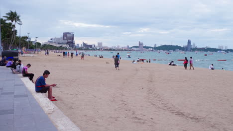People-and-children-and-tourists-enjoying-the-wide-and-long-shoreline-of-a-beach-strolling-sitting-down-playing-on-the-sand-taking-fresh-air