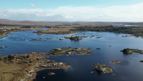 Aerial-view-over-the-picturesque-river-with-blue-reflecting-water-with-scattered-islands-and-lush-vegetation-from-connemara-lake-in-galway-during-an-exciting-trip-to-ireland