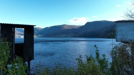 Two-historic-salmon-fishing-huts-at-Stavenes-with-view-towards-Vaksdal,-Norway