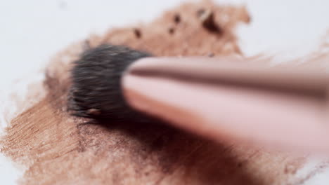 Smudging-a-mixture-of-powder-and-liquid-make-up-foundation-with-a-brush-applicator-on-a-white-board-palette